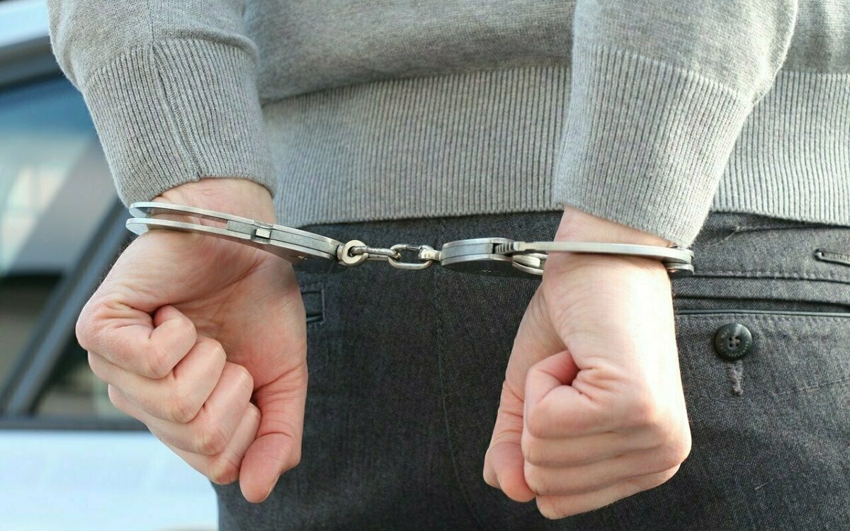 Hände mit Polizei-Handschellen nach einer Festnahme zusammengehalten Hände mit Polizei-Handschellen nach einer Festnahme zusammengehalten